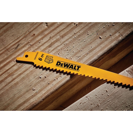 Close-up image of a yellow DEWALT saw blade with sharp teeth and 6 TPI marking, placed on a wooden surface.