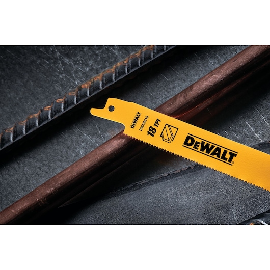Close-up of a DEWALT DW4811 yellow reciprocating saw blade with 18 TPI (teeth per inch), lying on metal pipes. The blade is labeled for cutting metal materials and features the DEWALT brand logo.