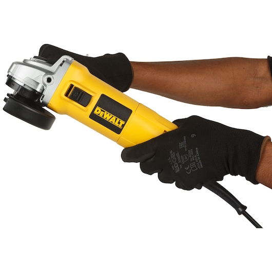 A person wearing black gloves holding a yellow DEWALT DW802 angle grinder against a white background.