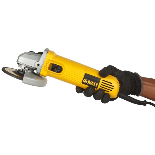 A person wearing a black glove is holding a yellow DEWALT angle grinder with a power cord, viewed from the side against a white background.