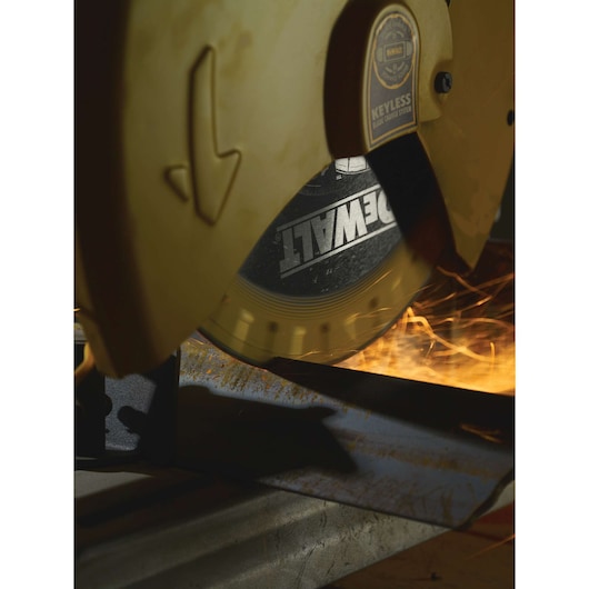 Close-up view of a DEWALT metal cutting saw in use, generating sparks as it cuts through a steel bar.