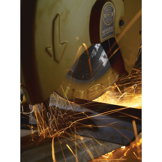Close-up of a DEWALT power chop saw cutting metal, with bright sparks flying from the blade during operation.