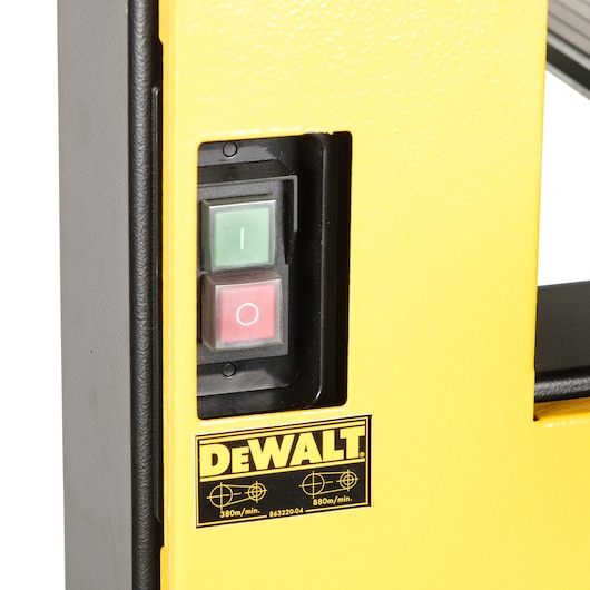 Close-up view of a DEWALT machine, showing a yellow panel with two buttons (a green 'on' button and a red 'off' button) and a DEWALT logo below them.