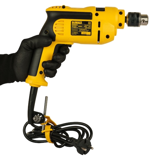 A yellow and black DEWALT DWD022 electric drill is held in a gloved hand, with a cord and plug wrapped around the handle. There is a metal key attached to the cord.
