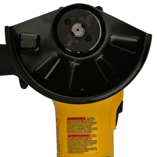 Close-up view of a DEWALT power tool, specifically showing the front part of a yellow and black angle grinder with a protective guard and warning label visible on the body.