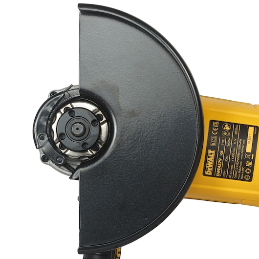 Close-up view of a DEWALT DWE4579 angle grinder with a black protective guard and yellow body, showing product details and safety information.