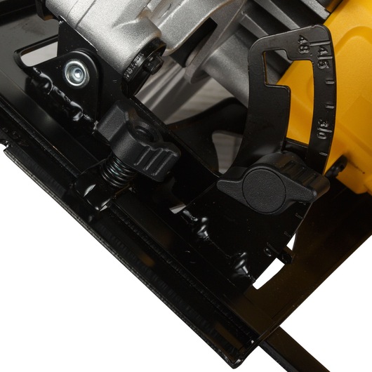 Close-up view of the angle adjustment mechanism and base plate of a DEWALT circular saw, showing detail of bevel marking and locking knobs.