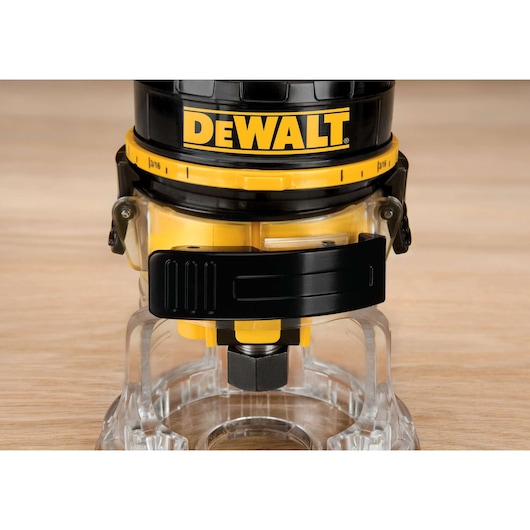 Close-up image of a DEWALT DWE6000 wood router showing the base and adjustment mechanisms on a wooden surface.