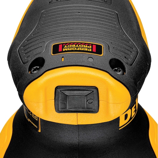 Close-up view of a DEWALT power tool, showing the top part of the tool with a textured black and yellow surface, a rectangular button, and a label marked 'PERFORM PROTECT.'