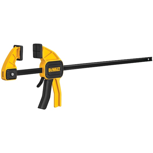 A DEWALT trigger clamp with a yellow and black design, used for holding materials together during woodworking or photography setups.