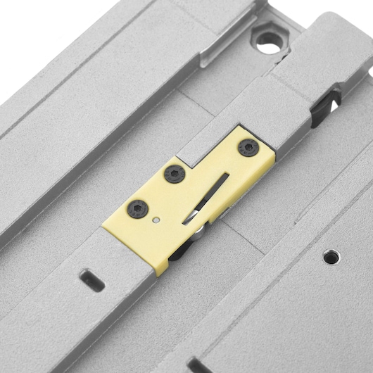 Close-up view of a part of a DEWALT track saw, featuring a metallic surface with a yellow component secured by black screws.