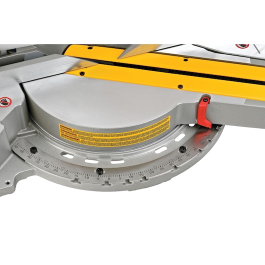 Close-up view of the base and angle adjustment scale of a DEWALT DWS780 miter saw, showing the yellow and grey parts with detailed degree markings and a red locking lever.