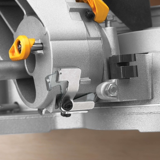 Close-up view of part of a DEWALT DWS780 miter saw, showing the adjustment knobs and metal components in detail.