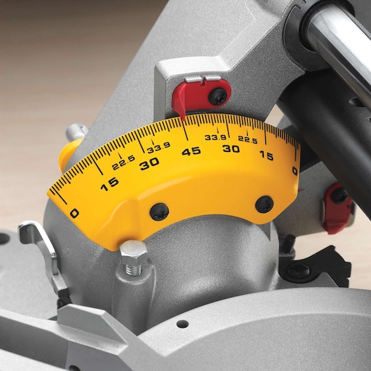 Close-up view of the yellow and silver angle adjustment scale on a DEWALT miter saw, showing measurement markings from 0 to 45 degrees.
