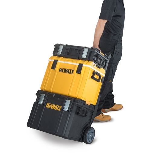 A person is transporting a stack of DEWALT branded, wheeled toolboxes, featuring yellow and black compartments.