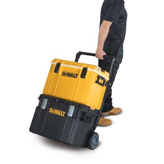 A person is pulling a DEWALT rolling tool box set with a yellow top box and a black bottom box on wheels.
