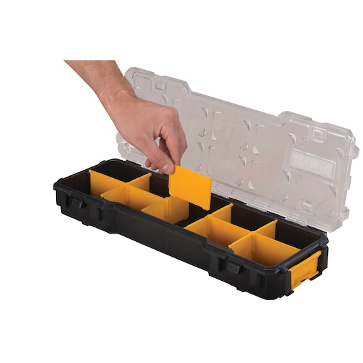 A hand is placing a yellow divider into a black DEWALT organizer box with a transparent lid. The box contains multiple yellow compartments for sorting small items.