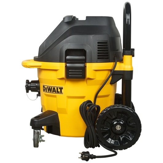 A DEWALT DWV902M industrial vacuum cleaner with large wheels, black handle, and a yellow and black body. The power cord is wrapped around the side and the plug is visible at the front.