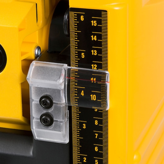 Close-up of a DEWALT DW733 yellow power tool showing a precision measurement scale with clear plastic indicator and black adjustment screws.