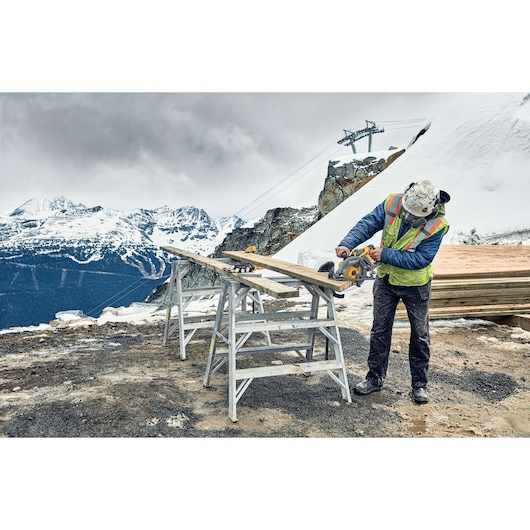 FLEXVOLT cordless worm drive style saw being used by person to cut wooden plank outdoors.