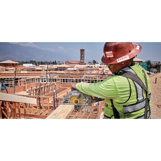 FLEXVOLT cordless worm drive style saw being used by person to cut wooden plank.