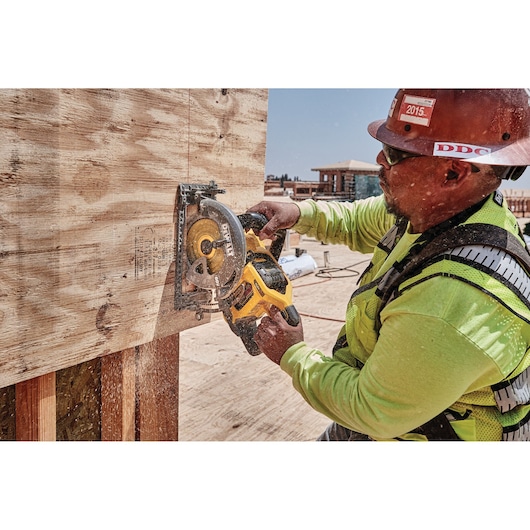 FLEXVOLT cordless worm drive style saw being used by person to cut wooden sheet.