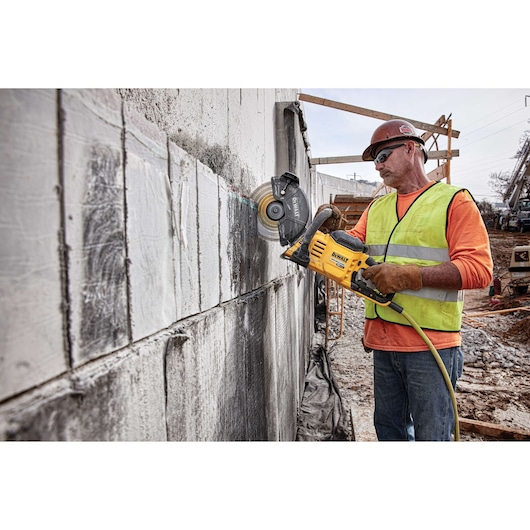 Brushless cordless cut-off saw being used by person on concrete vertically.