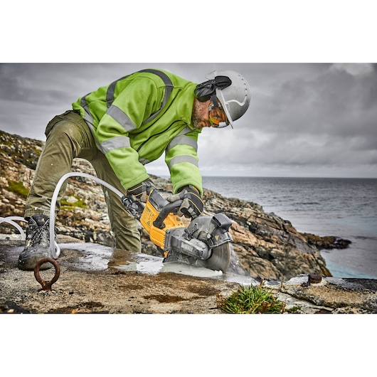 Brushless cordless cut-off saw being used by person on cement wall.
