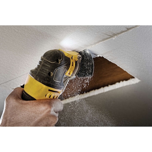 Oscillating multi tool kit being used to cut into ceiling.