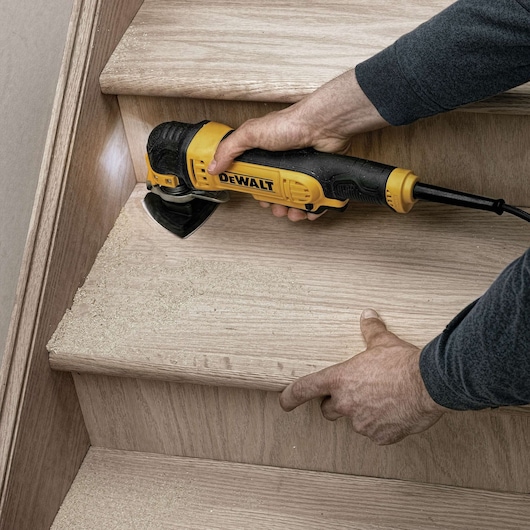Oscillating multi tool kit being used to sand wood.