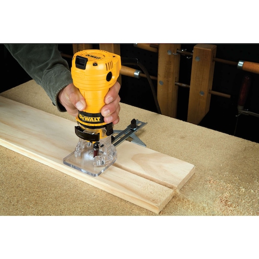 Laminate trimmer being used to cut a wooden board.
