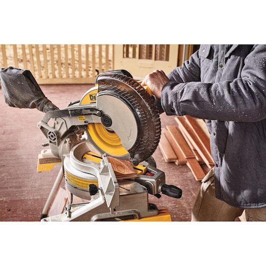 Electric single bevel compound miter saw being used to cut wood.